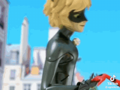 Cat Noir Standing In Front Of City Holding Red Object GIF