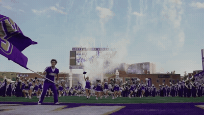 Cheerleader Holding Purple Flag In Front Of James Madison University Scoreboard GIF