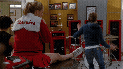 Cheerleader In Cheerios Jacket On Bench GIF