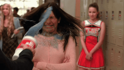 Cheerleader In Gray Uniform Behind Woman With Cup On Head GIF
