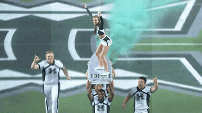 Cheerleader Lifted by Players With Letter H on Uniforms