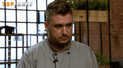 Chef In Uniform In Front Of Top Chef Screen GIF