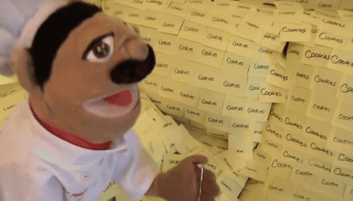 Chef Puppet In Front Of Sticky Note Wall With Cookies GIF