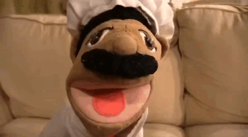 Chef Puppet With Hat And Mustache On Couch Tongue Out GIF