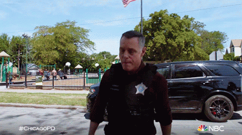 Chicago Police Officer Walking Down Street In Front Of Park GIF