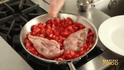 Chicken And Tomatoes Are Being Cooked In A Frying Pan With Everyday Food Written On The Stove GIF