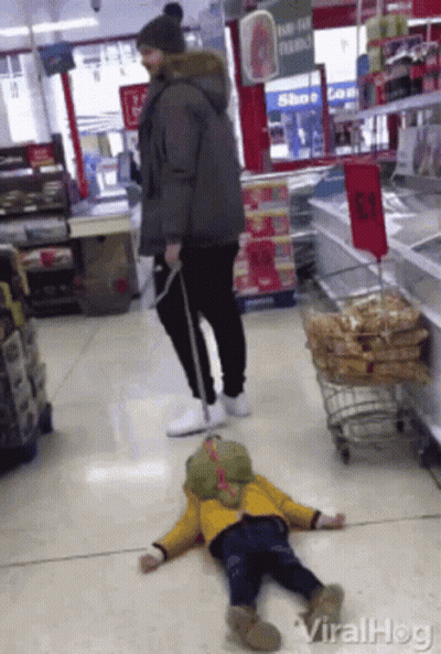 Child Laying On Store Floor With Man Standing Behind GIF