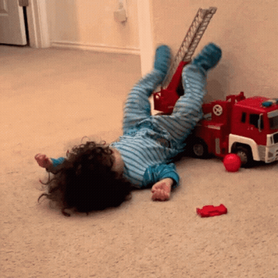 Child Lying Next To Toy Fire Truck GIF