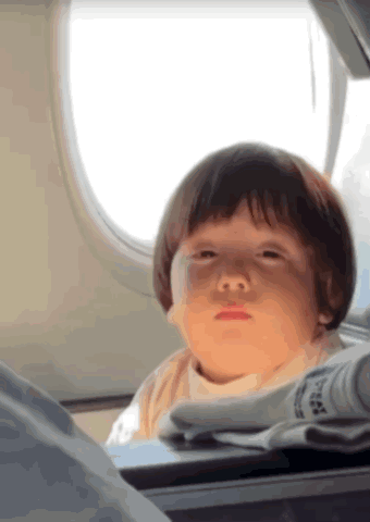 Child Sitting On Airplane Looking Out Window GIF