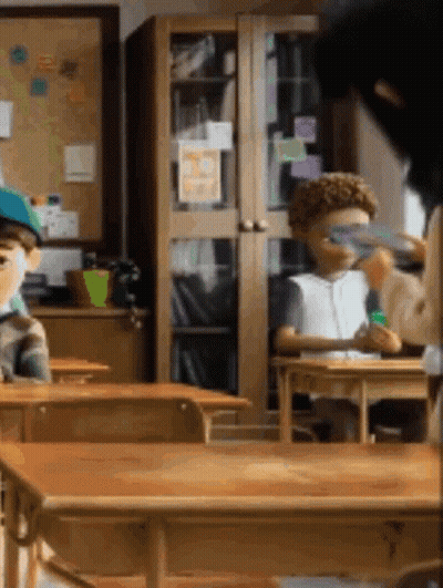 Children Sitting At Desks In Classroom With Bulletin Board GIF