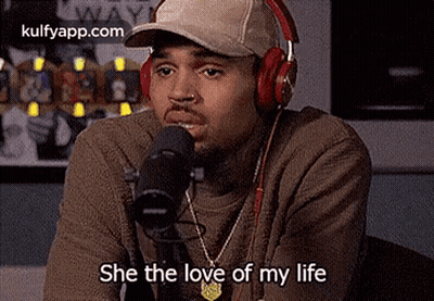 Chris Brown Is Wearing Headphones And A Hat While Talking Into A Microphone . GIF