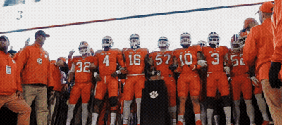 Clemson Football Players In Orange Uniforms With Trophy GIF