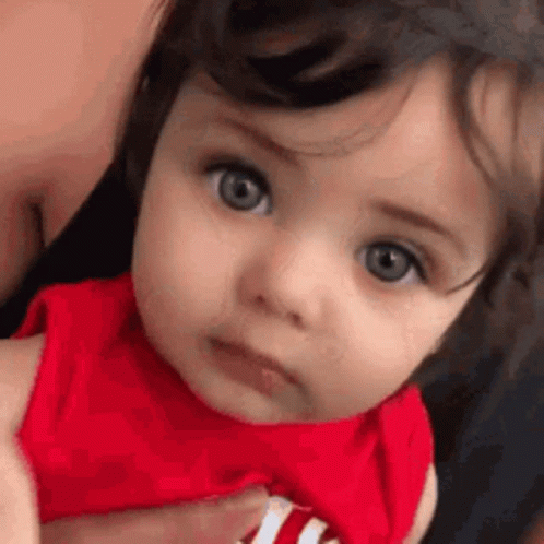 Close Up Of Baby In Red Shirt Looking At Camera GIF