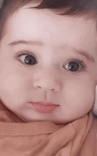 Close Up Of Baby With Big Eyes And Pink Shirt GIF