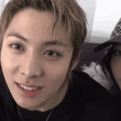 Close Up Of Man With Woman In Baseball Cap Behind Him GIF