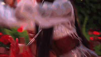 Close Up Of Person's Face With Blurred Flowers And Trees GIF
