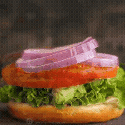 Close Up Of Sandwich With Lettuce Tomato And Onions On Bun GIF