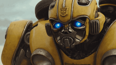 Close Up Yellow Robot With Blue Eyes And Transformer Logo GIF