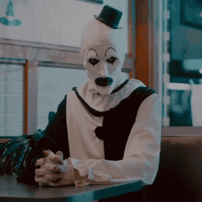 Clown Sitting At Table With Hands Folded GIF
