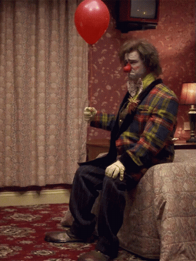 Clown Sitting On Bed With Red Balloon GIF