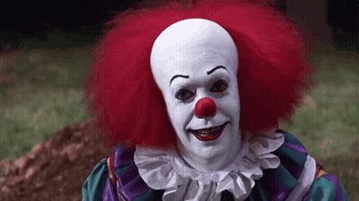 Clown With Red Hair And Red Nose Standing In Grass GIF