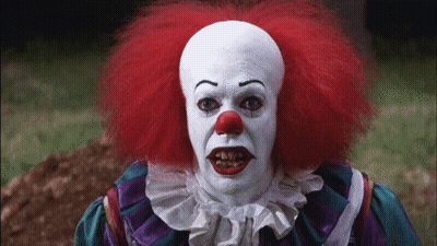 Clown With Red Hair And White Face Paint Looking At Camera GIF