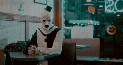 Clown With Top Hat Sitting At Table GIF
