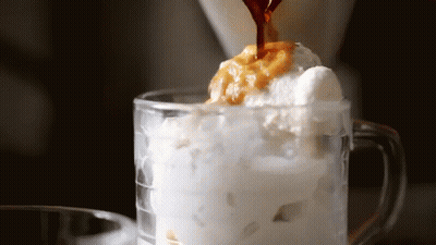 Coffee Is Being Poured Into A Glass Of Ice Cream And Whipped Cream GIF