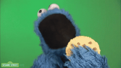 Cookie Monster From Sesame Street Eating A Cookie On A Green Background GIF