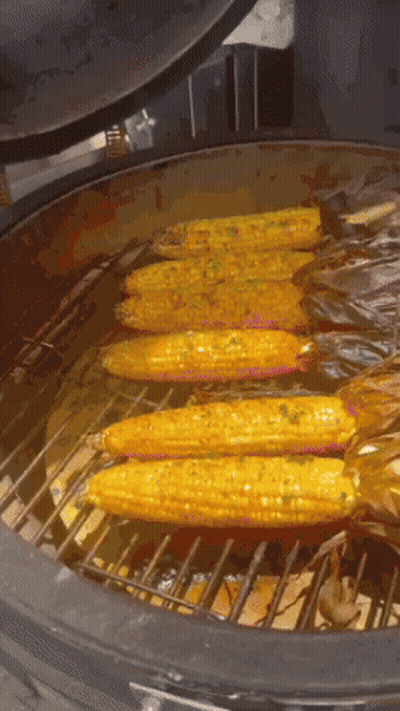 Corn On The Cob Is Being Cooked On A Grill With The Lid Open GIF