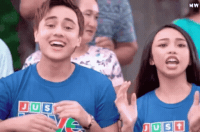 Couple Clapping In Crowd With Blue Shirts Saying Just Love GIF