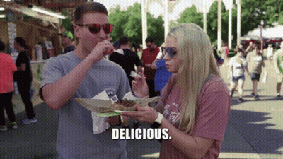 Couple Eating At Festival Woman Says Delicious GIF