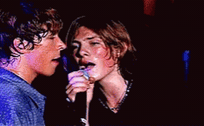 Couple Singing Into Microphones Eyes Closed GIF