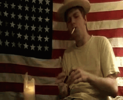 Cowboy Smoking In Front Of American Flag GIF