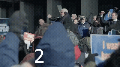 Crowd Holding Signs Including I Want Better GIF