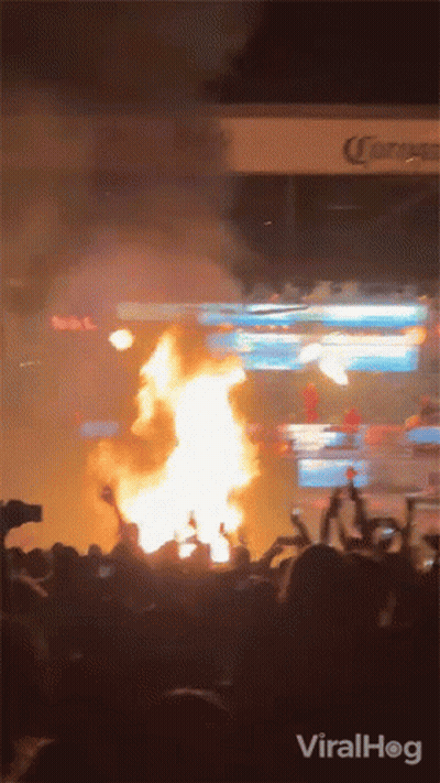 Crowd Watching Fire In Front Of Corona Sign GIF