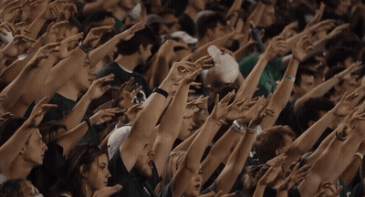 Crowd With Arms Up Including Green Shirt Saying Texas GIF