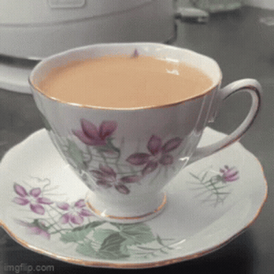 Cup Of Tea On Saucer With Purple Flowers GIF