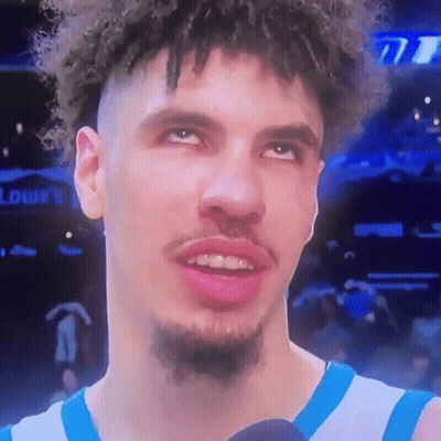 Curly-Haired Bearded Man in Blue-White Jersey on Mic