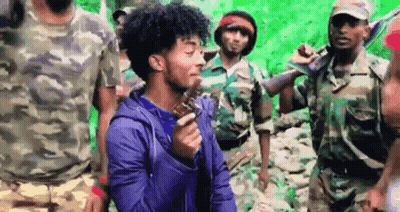Curly Haired Man Holding Gun In Front Of Soldiers GIF