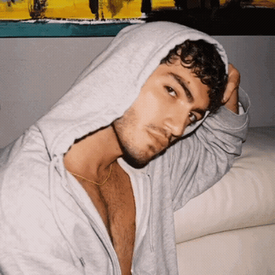 Curly Haired Man In Grey Hoodie Looking At Camera GIF