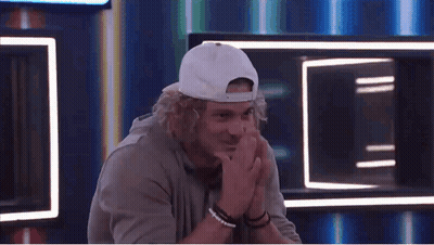 Curly-Haired Man In White Hat And Bracelets With Hands Folded GIF