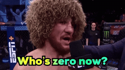 Curly Haired Man Into Mic Saying Who's Zero Now GIF