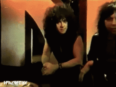 Curly Haired Man Next To Another Man At Spacefoxy Sign GIF