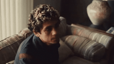 Curly Haired Man On Couch In Front Of Mirror GIF