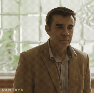 Curly-Haired Man Smiling In Front Of Somos Lo Mismo Sign GIF