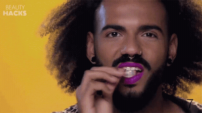 Curly Haired Man With Beard Applying Purple Lipstick GIF
