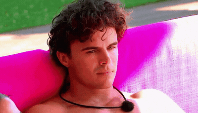 Curly-Haired Shirtless Man Laying On Pink Blanket Mic GIF