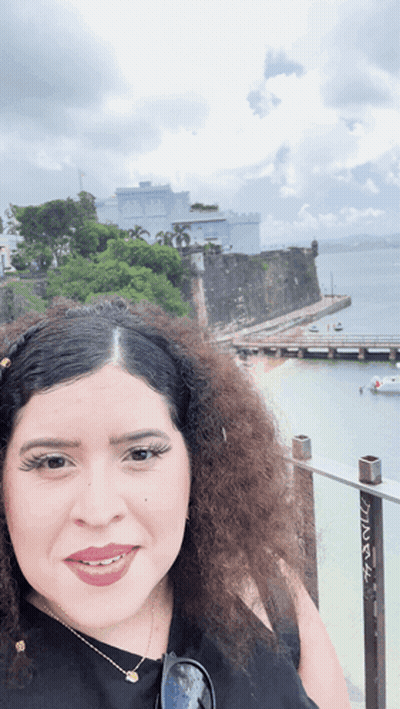 Curly Haired Woman By Water And Building GIF