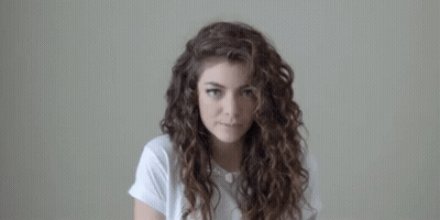 Curly-Haired Woman in White Shirt Looking at Camera